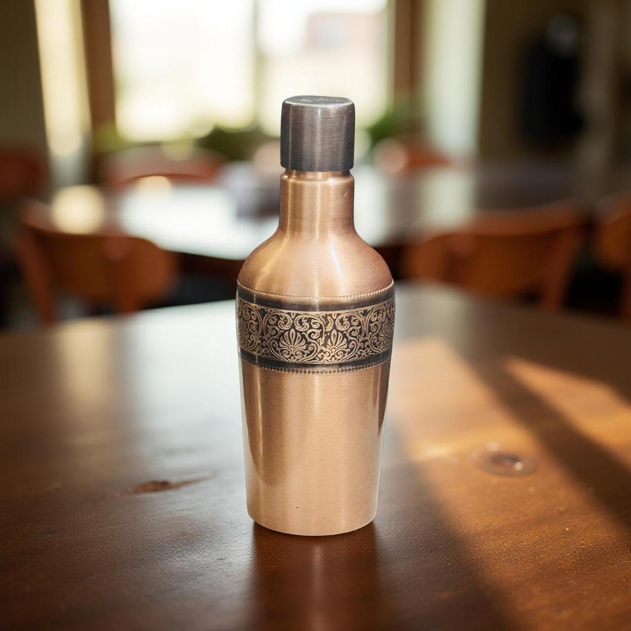 Decorative bronze bottle on a wooden table with a blurred indoor background