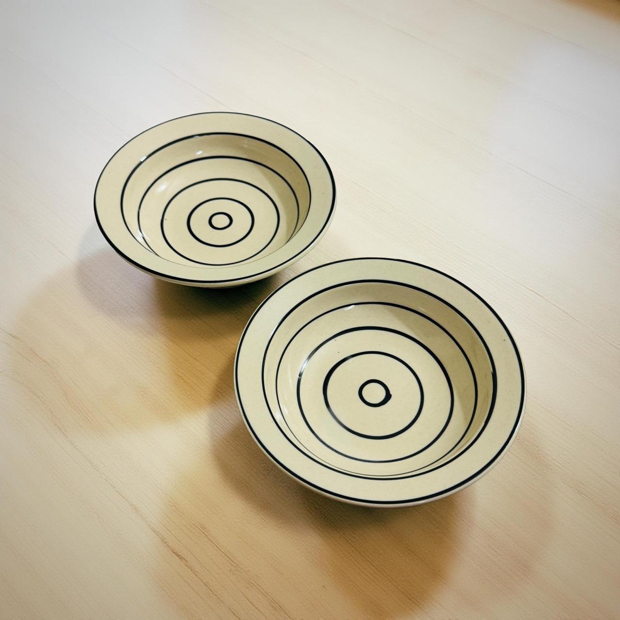 Two ceramic bowls with concentric circle patterns on a wooden surface