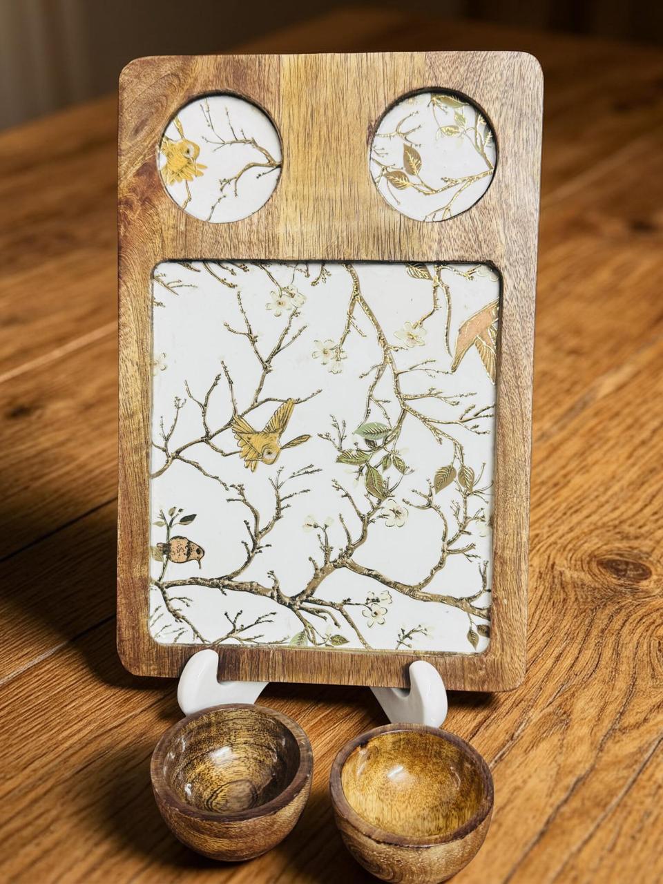 Wooden tray with decorative paper and two small bowls on a wooden surface