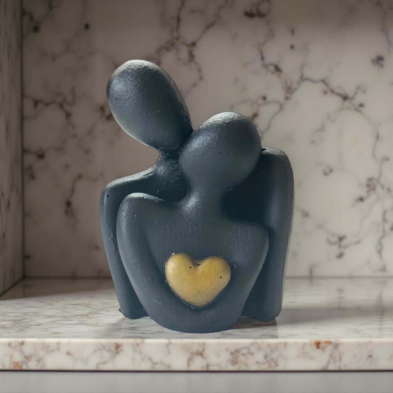 Decorative sculpture of two figures embracing with a heart on a marble surface