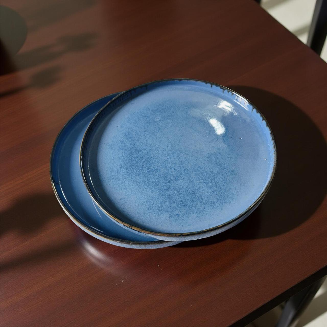 Two blue ceramic plates stacked on a wooden surface