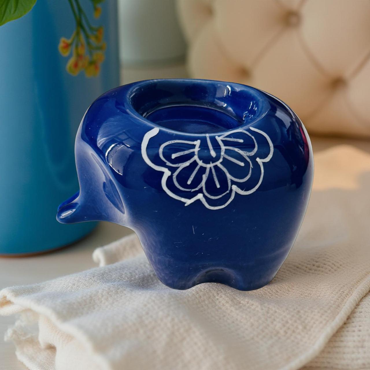 Blue ceramic elephant with white floral design on a beige surface