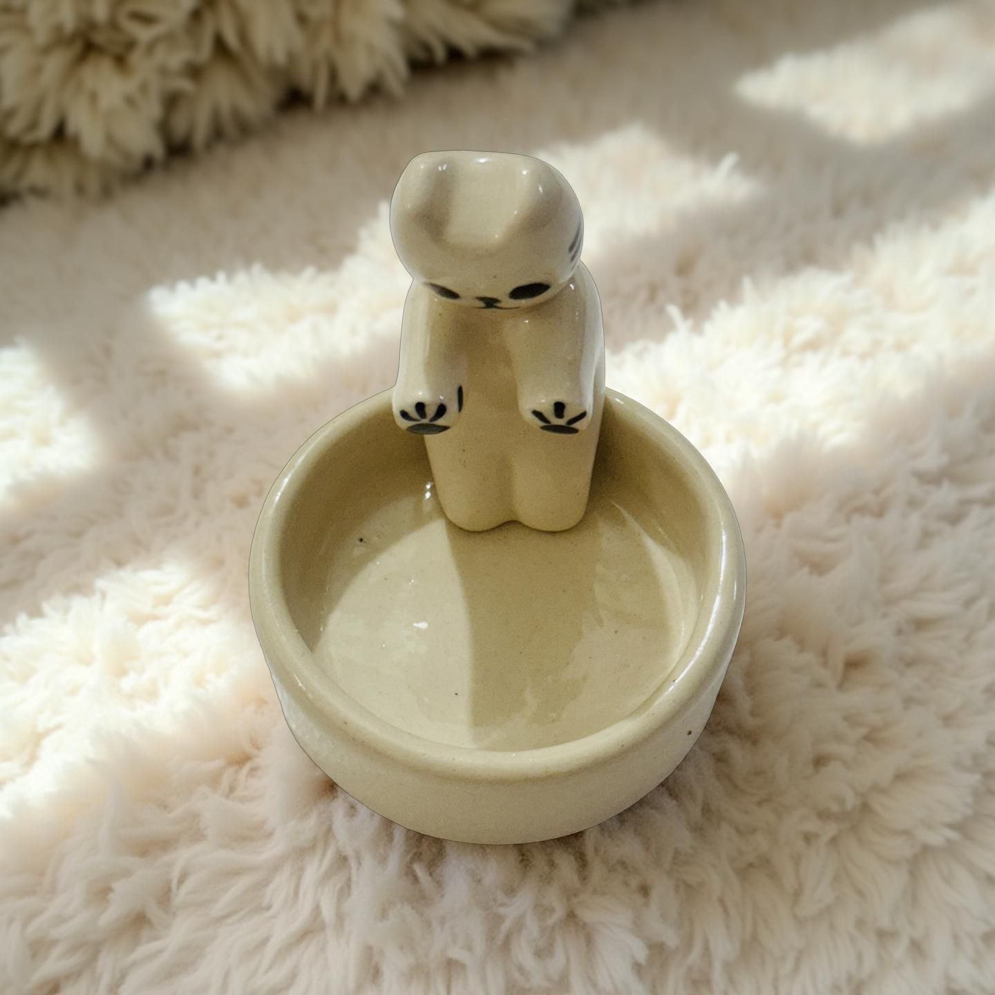 Ceramic bowl with a bear-shaped handle on a fluffy white surface