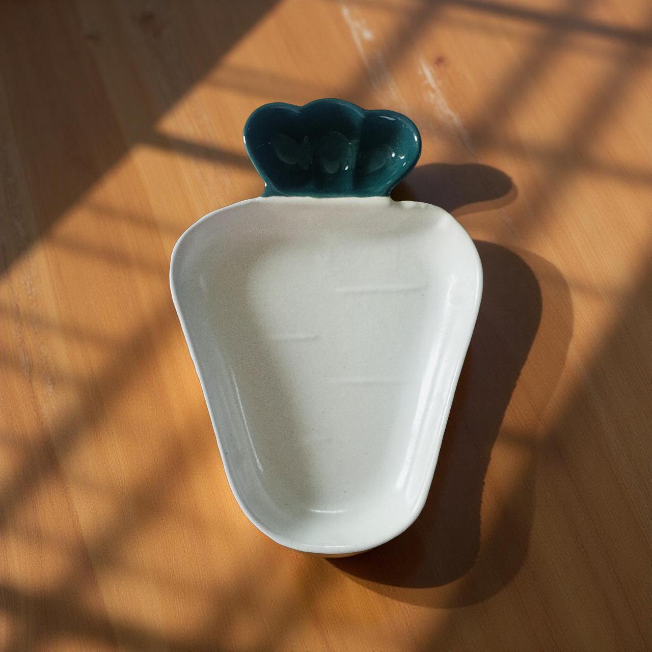 White ceramic dish with a green top on a wooden surface