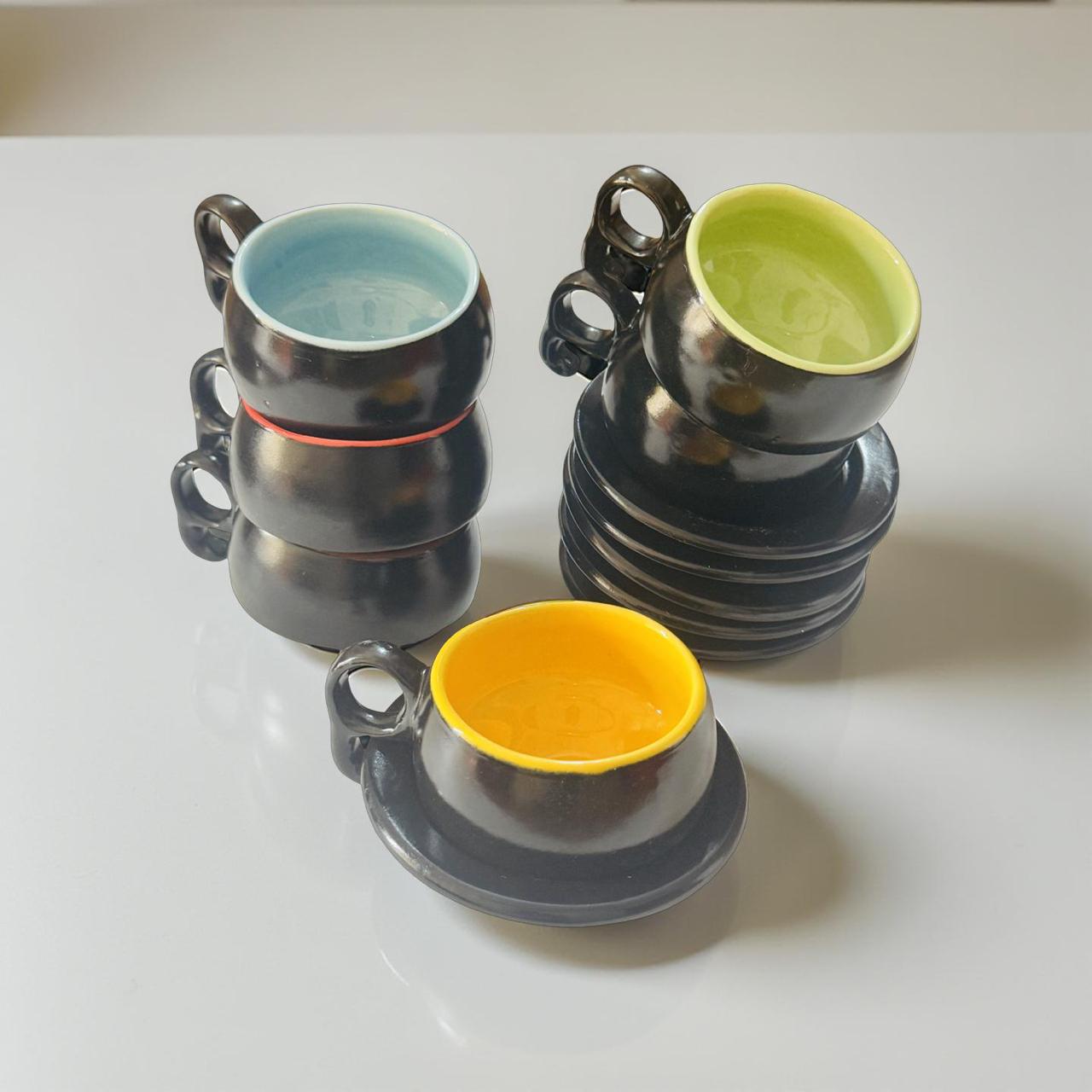 Set of ceramic cups with different colored interior and exterior finishes on a white surface.
