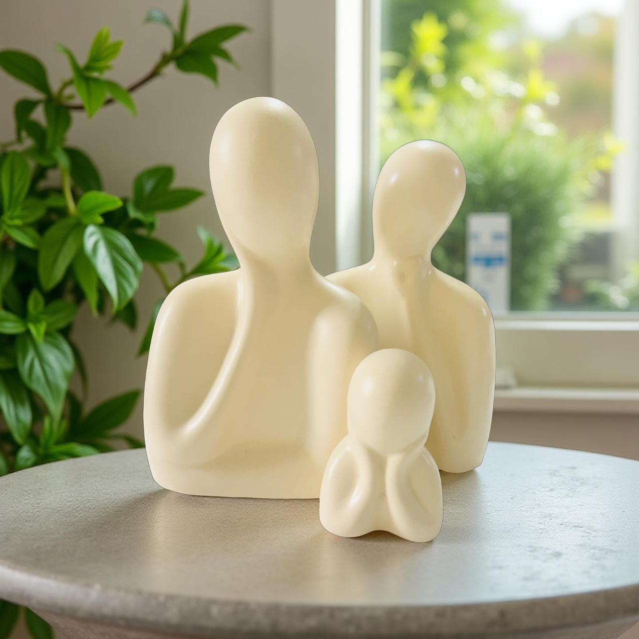White abstract sculpture of a family on a table with a window and plant in the background