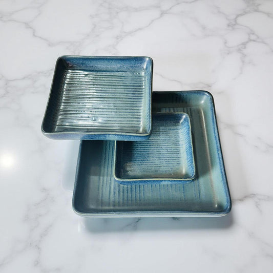 Two blue ceramic trays stacked on a marble surface
