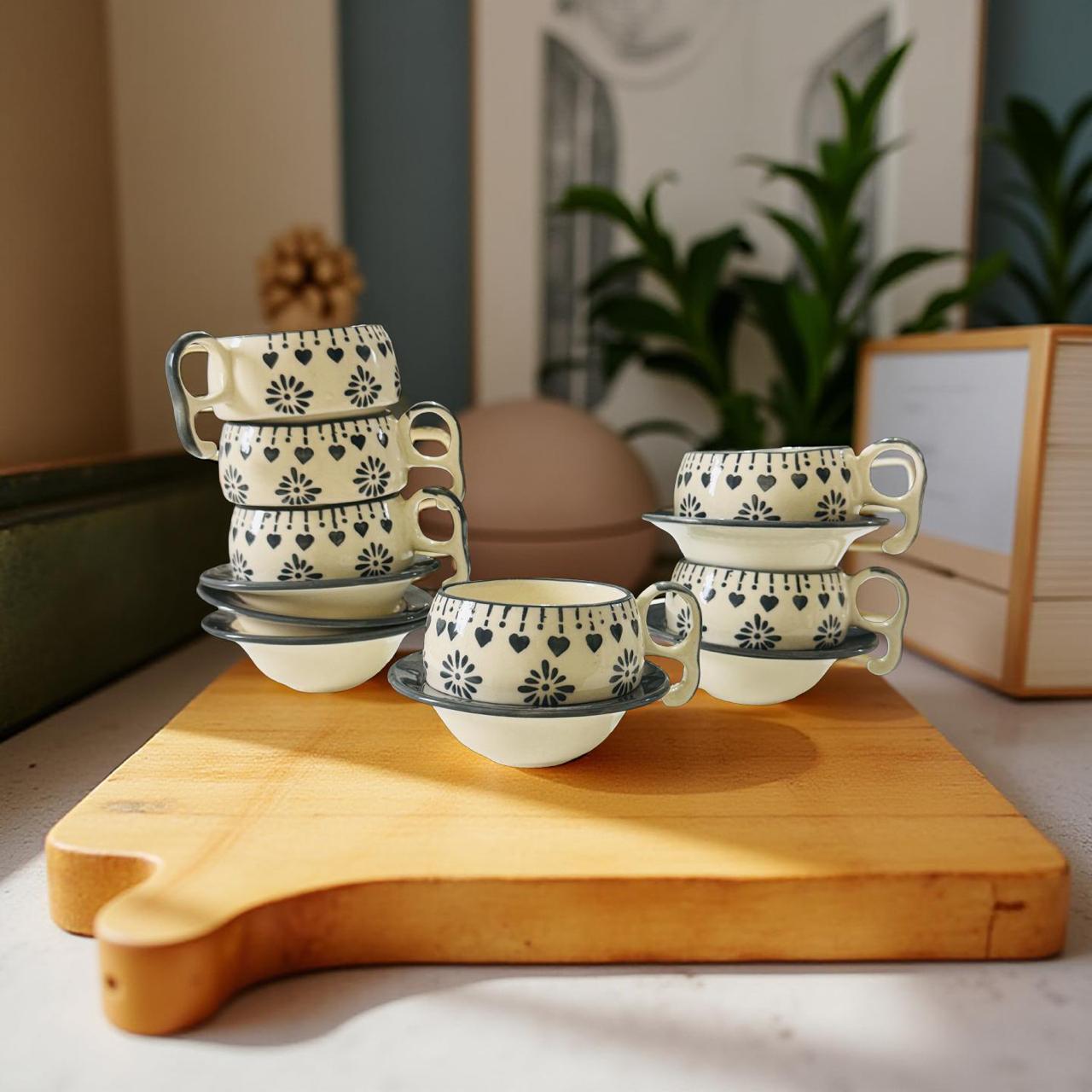 white ceramic mugs with gray floral design and saucers kept on a wooden cutout