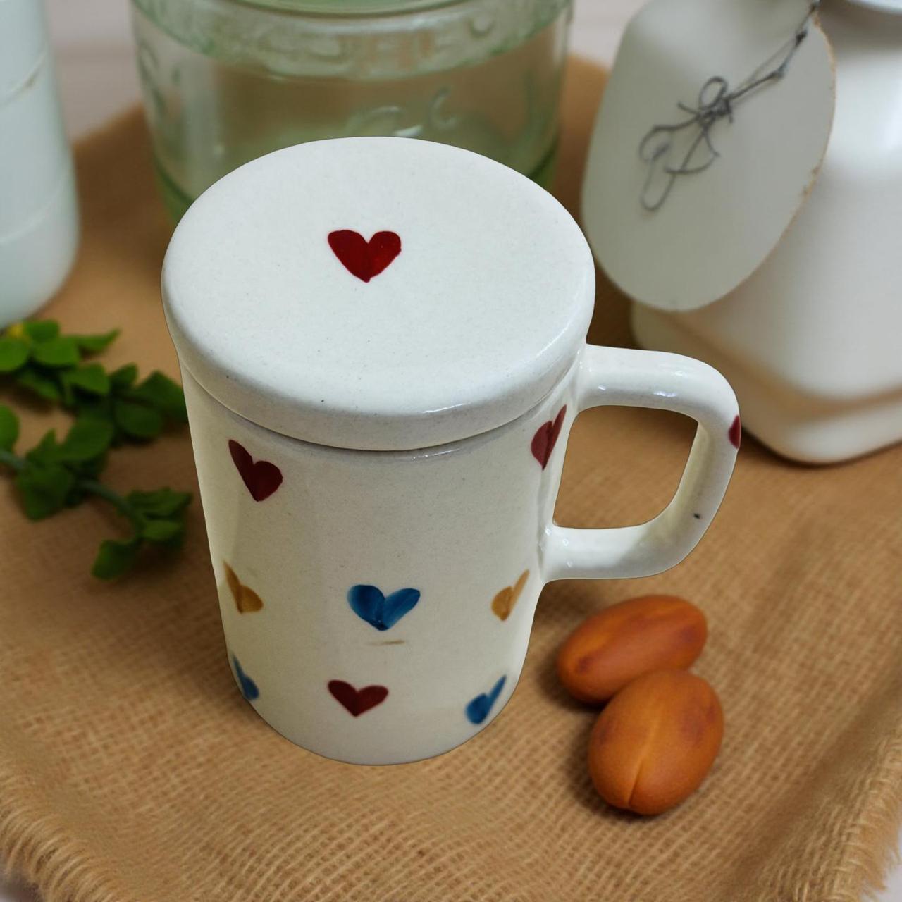 White mug with heart designs on a wooden surface with jars and fruits.