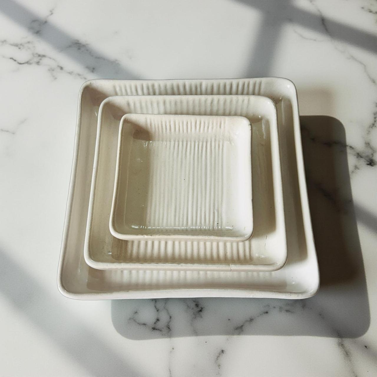 Set of three square ceramic trays on a marble surface