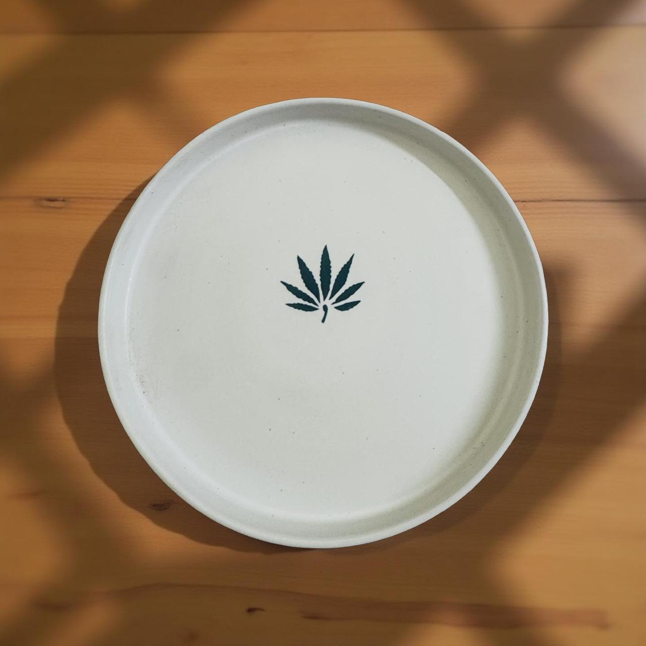 White plate with a cannabis leaf design on a wooden surface