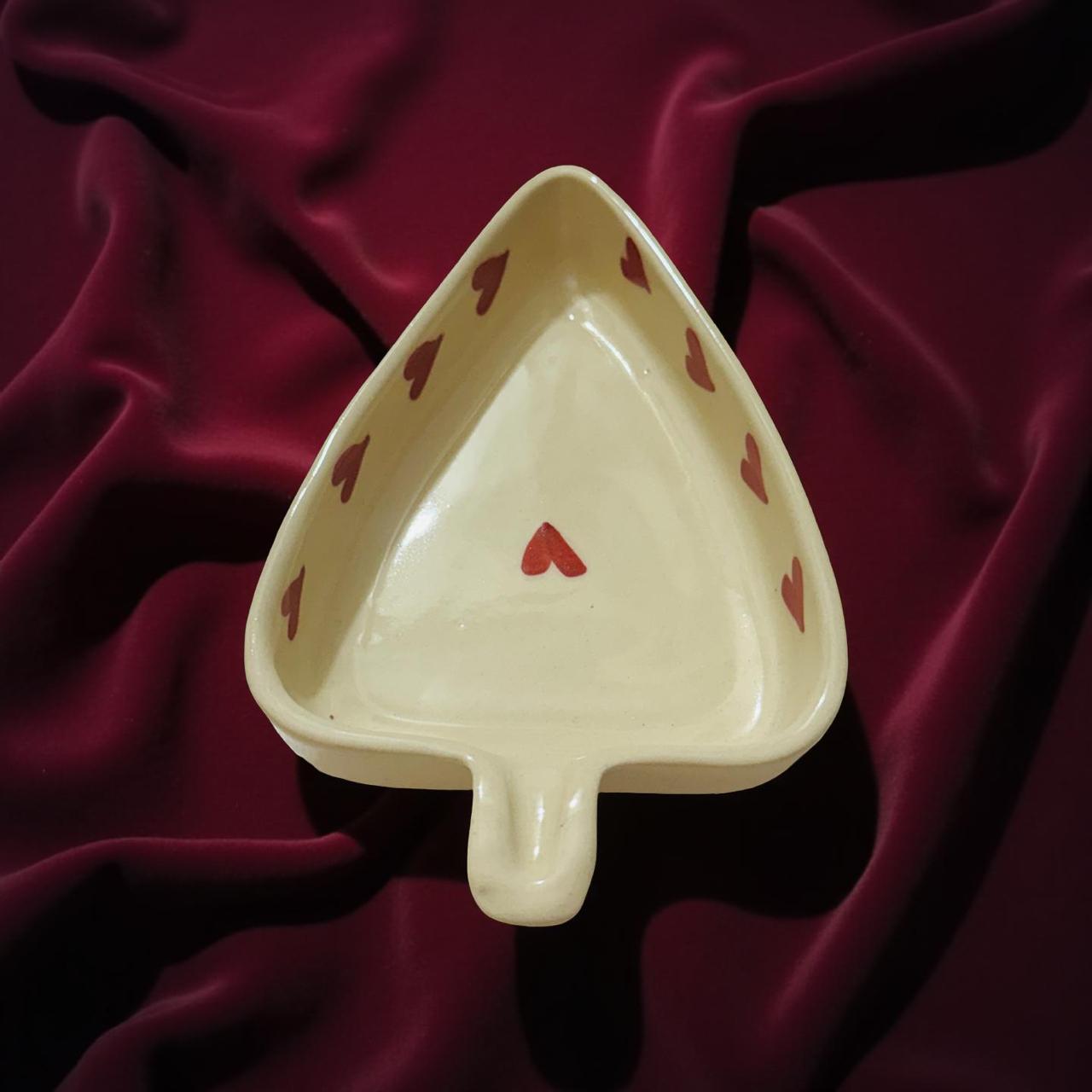 ceramic leaf shape bowl with red heart placed on a velvet cloth