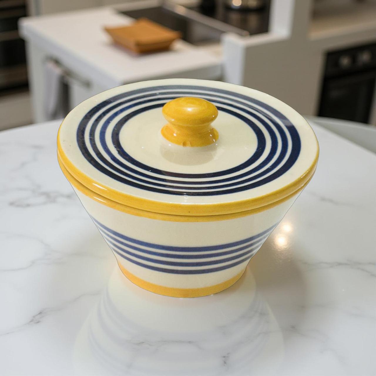 Ceramic container with blue and yellow stripes on a marble surface