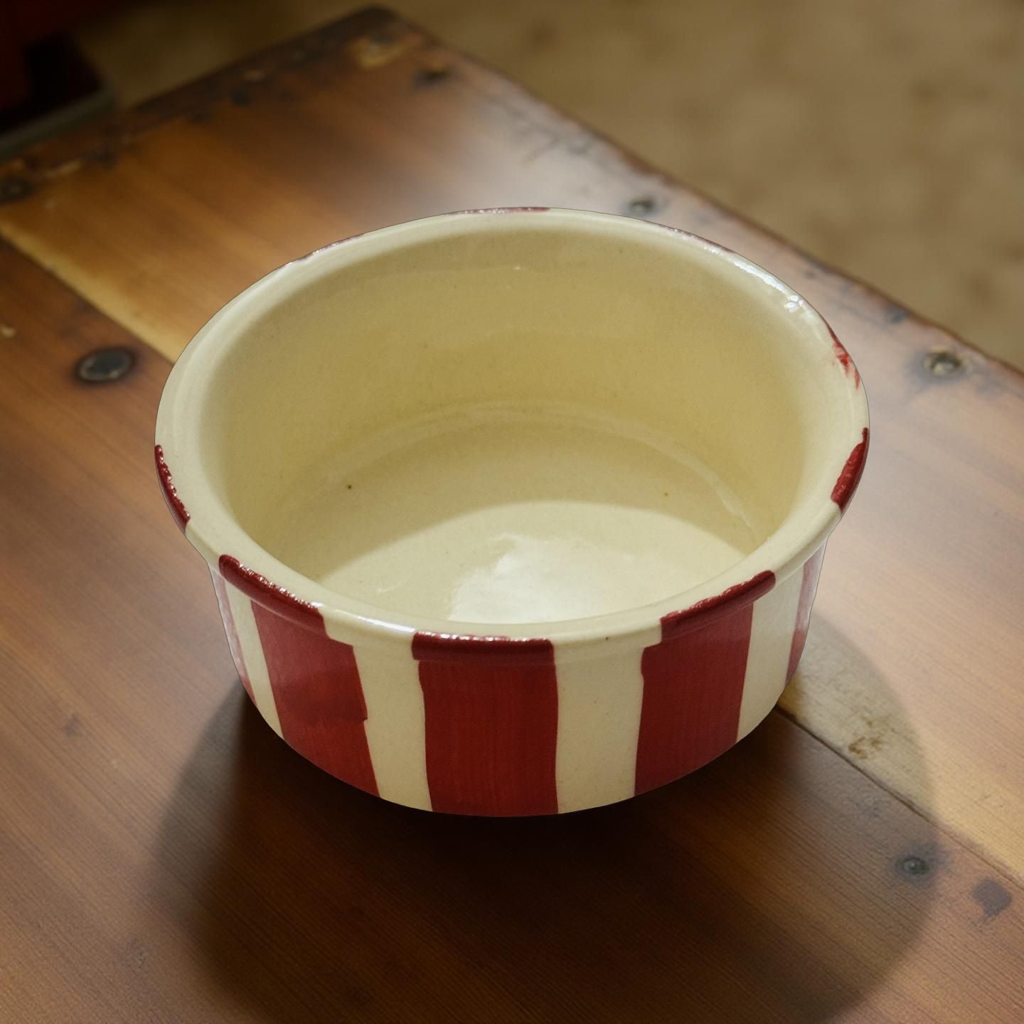 Ceramic bowl with red and white stripes on a wooden surface