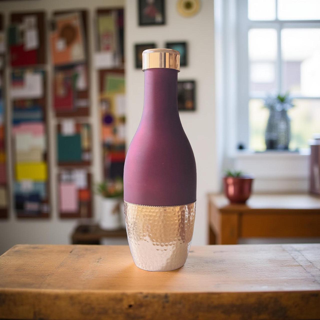 Purple and gold bottle on a wooden surface with a blurred indoor background