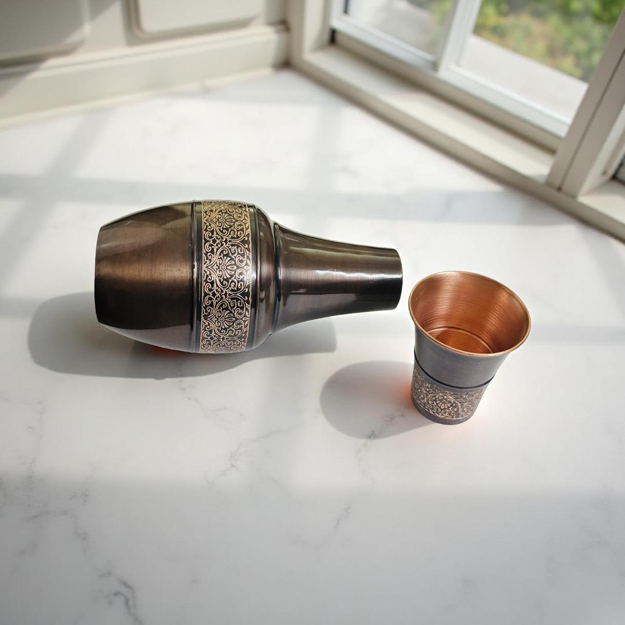 Decorative copper pot and glass on a marble surface with a window in the background