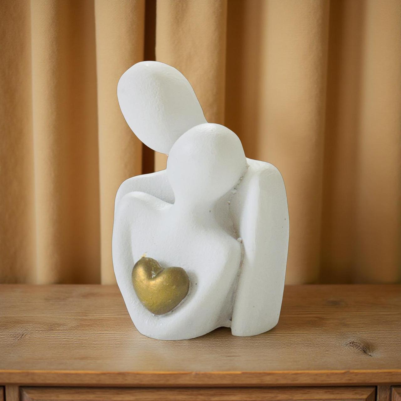 Abstract sculpture of two figures holding a heart on a wooden surface with a beige curtain background