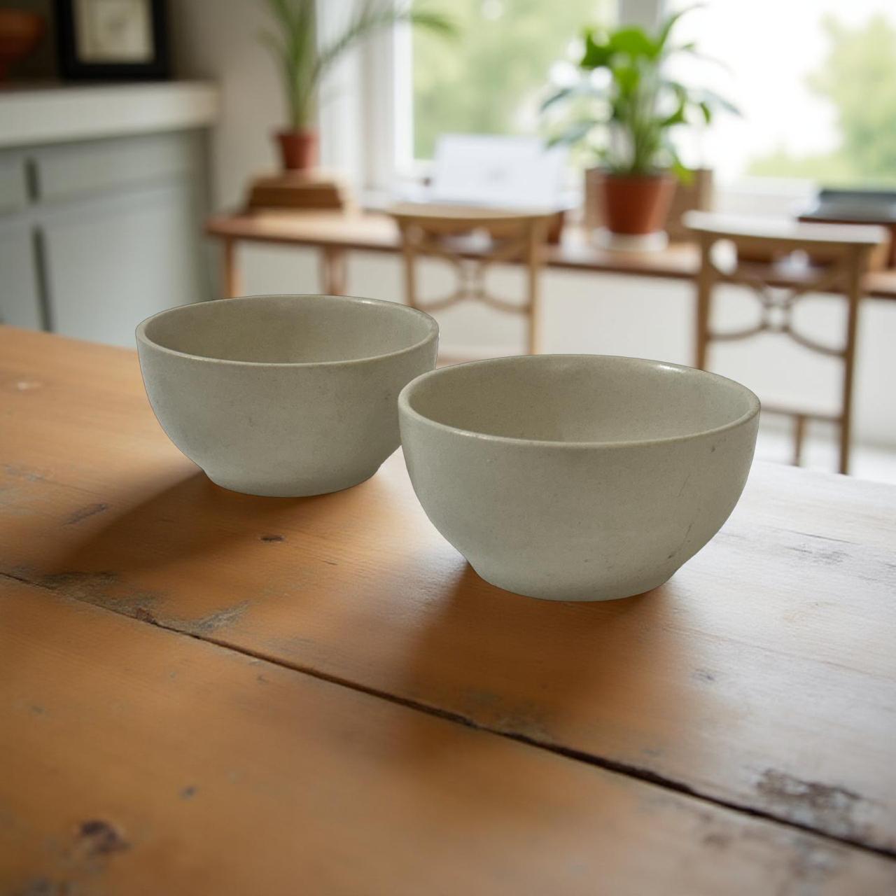 Two ceramic bowls on a wooden table with a blurred indoor background
