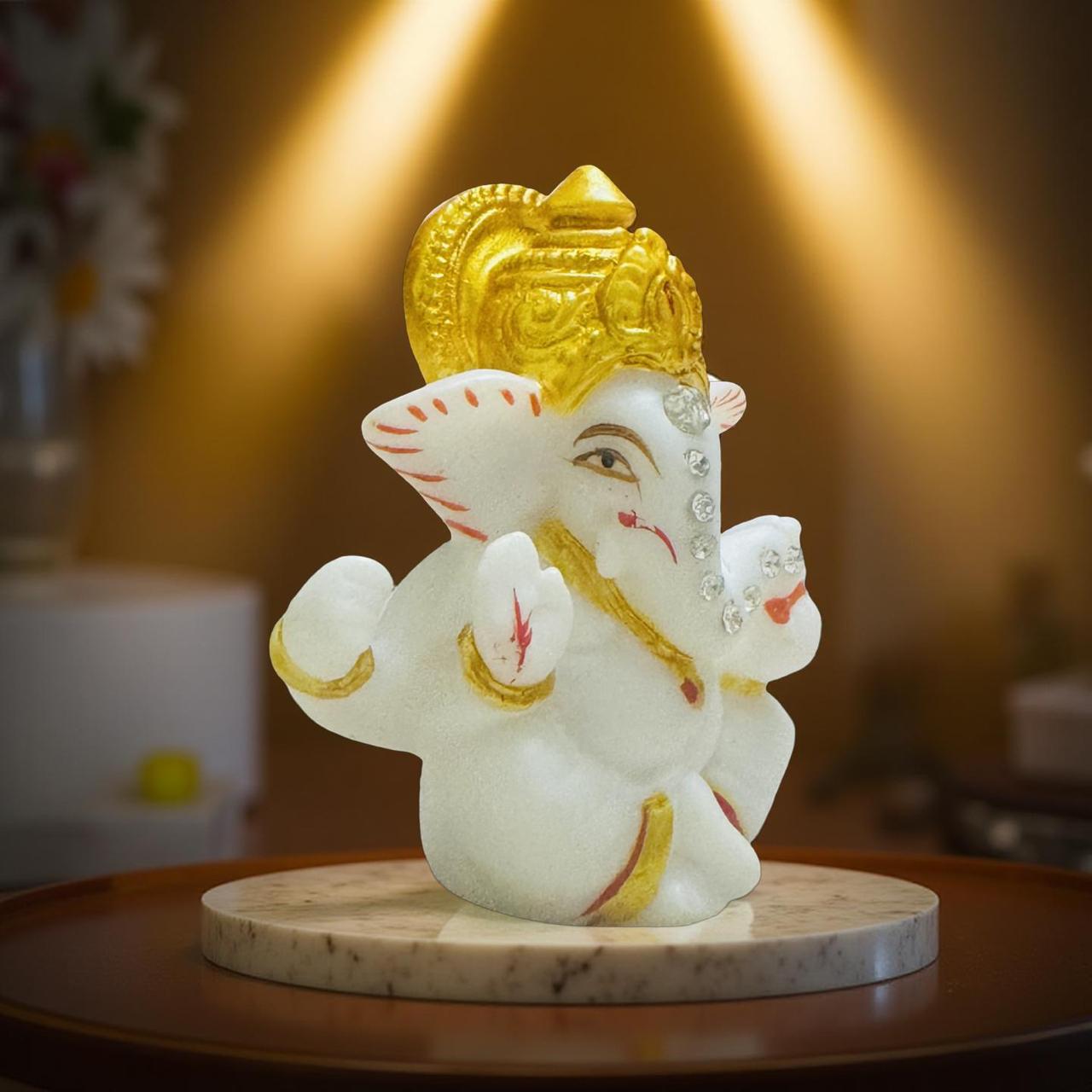 White and gold Ganesh statue on a wooden platform with a warm light background