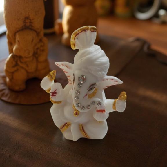 ganeshji ki murti on a wooden surface with blurred background