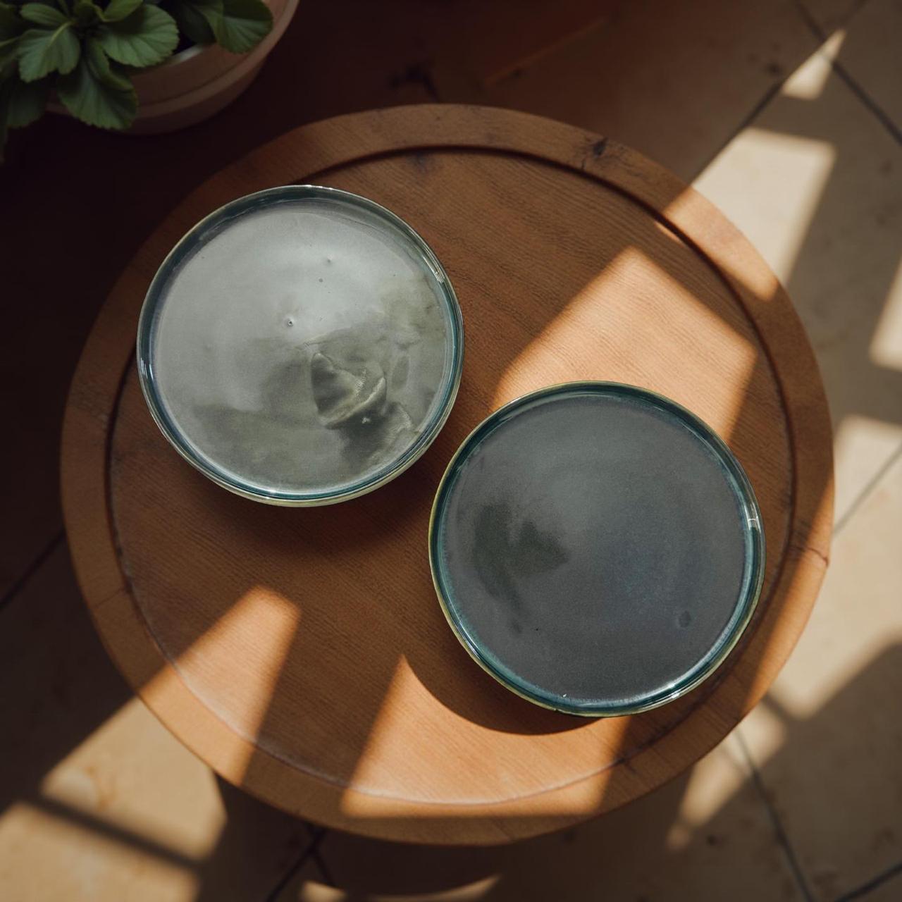 Two ceramic bowls on a wooden surface with sunlight casting shadows.