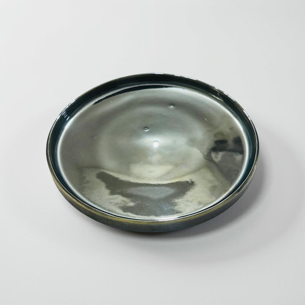 Round metallic object with a reflective surface on a white background