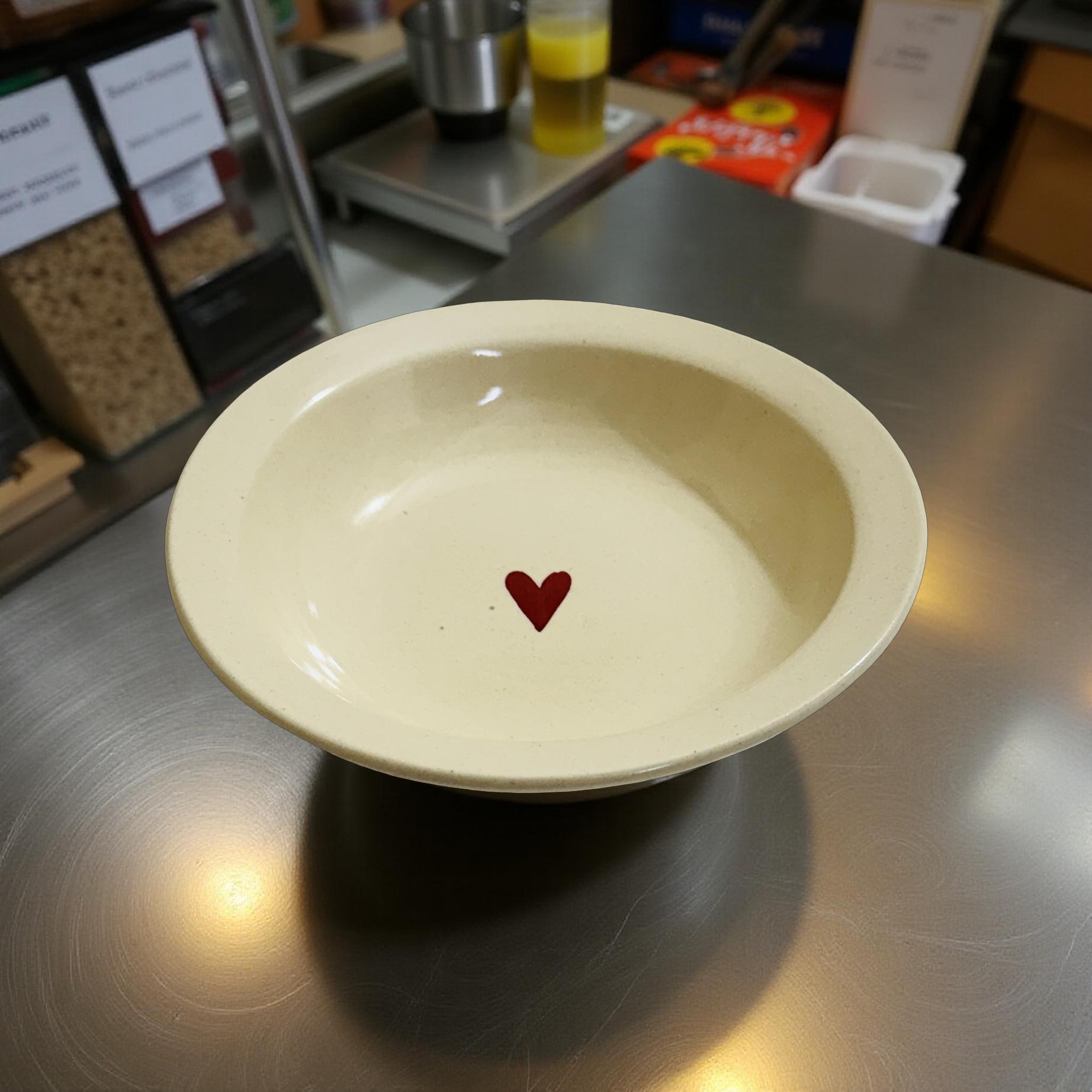 White bowl with a red heart on a metallic surface