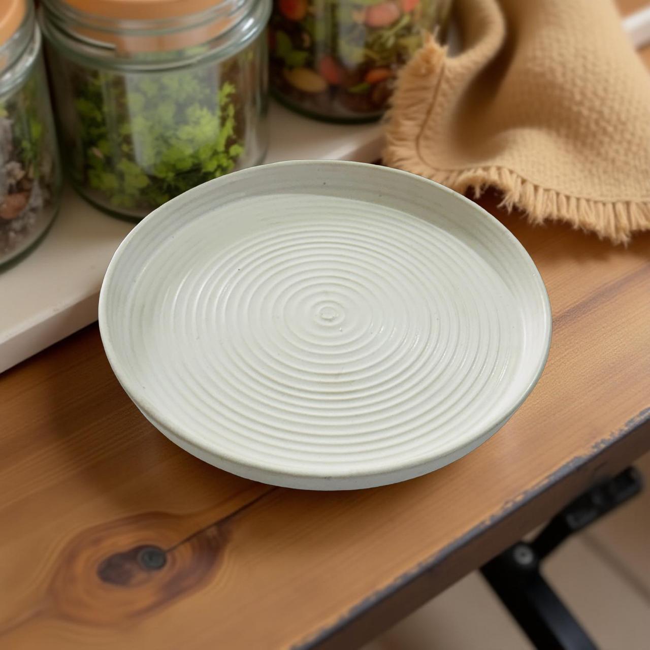 Light creme ceramic plate on a wooden surface with jars and a cloth in the background