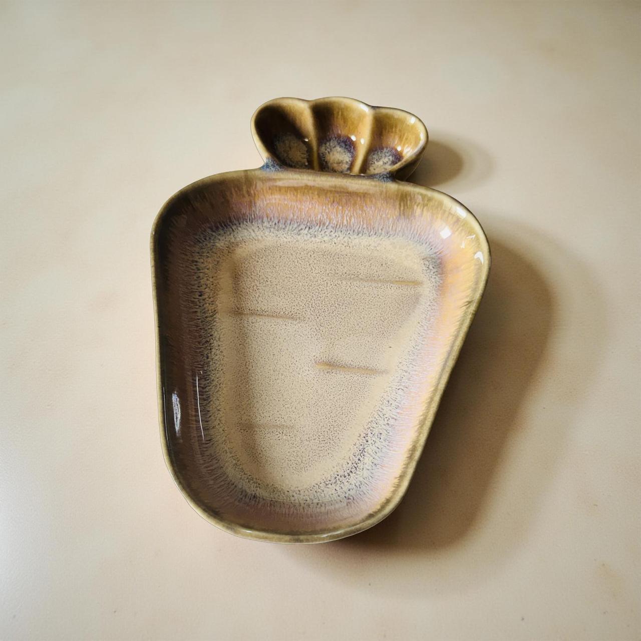 Ceramic dish with a shell-like design on a beige background