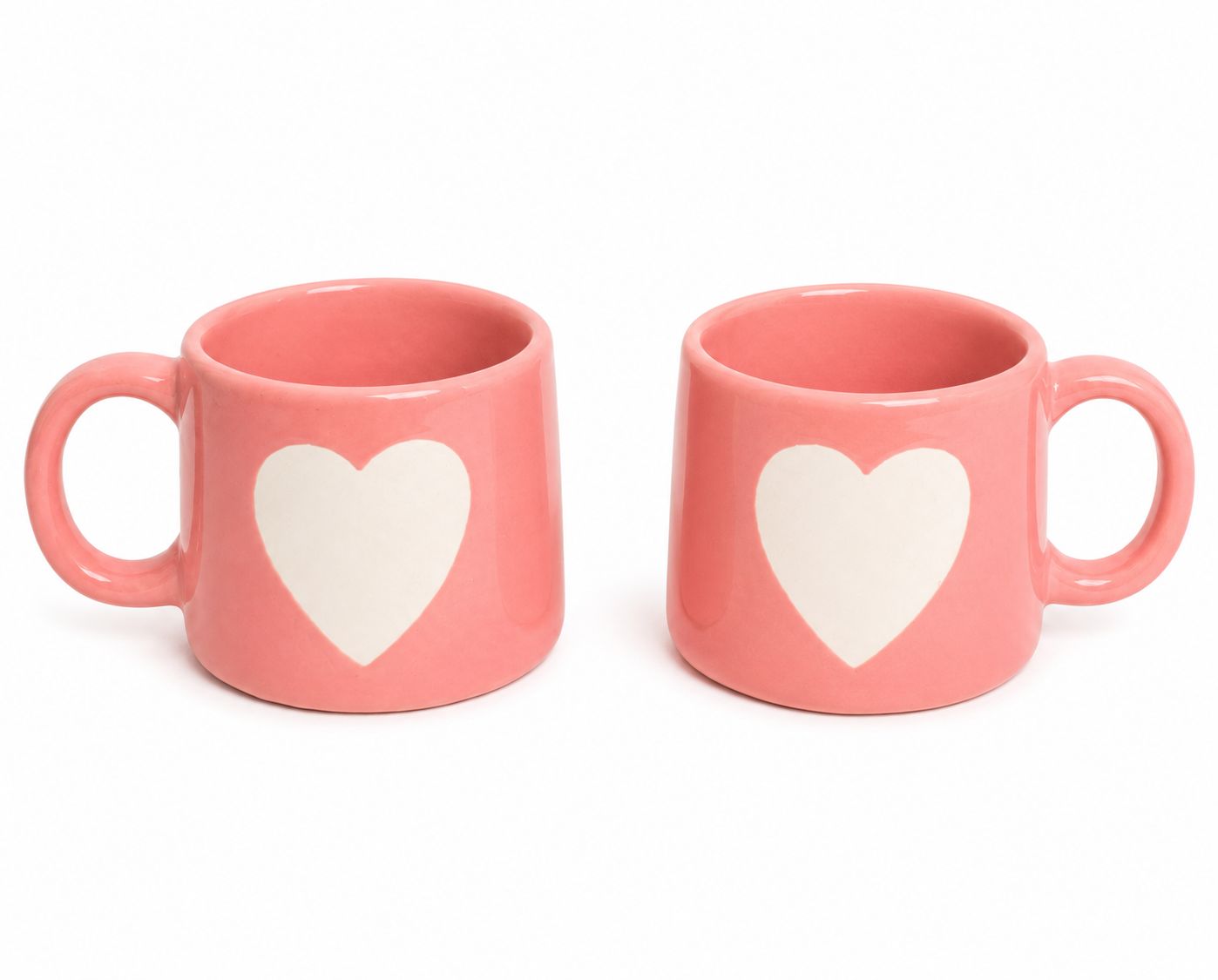 Two pink ceramic mugs with large white heart designs on the front, shown side by side on a plain white background.