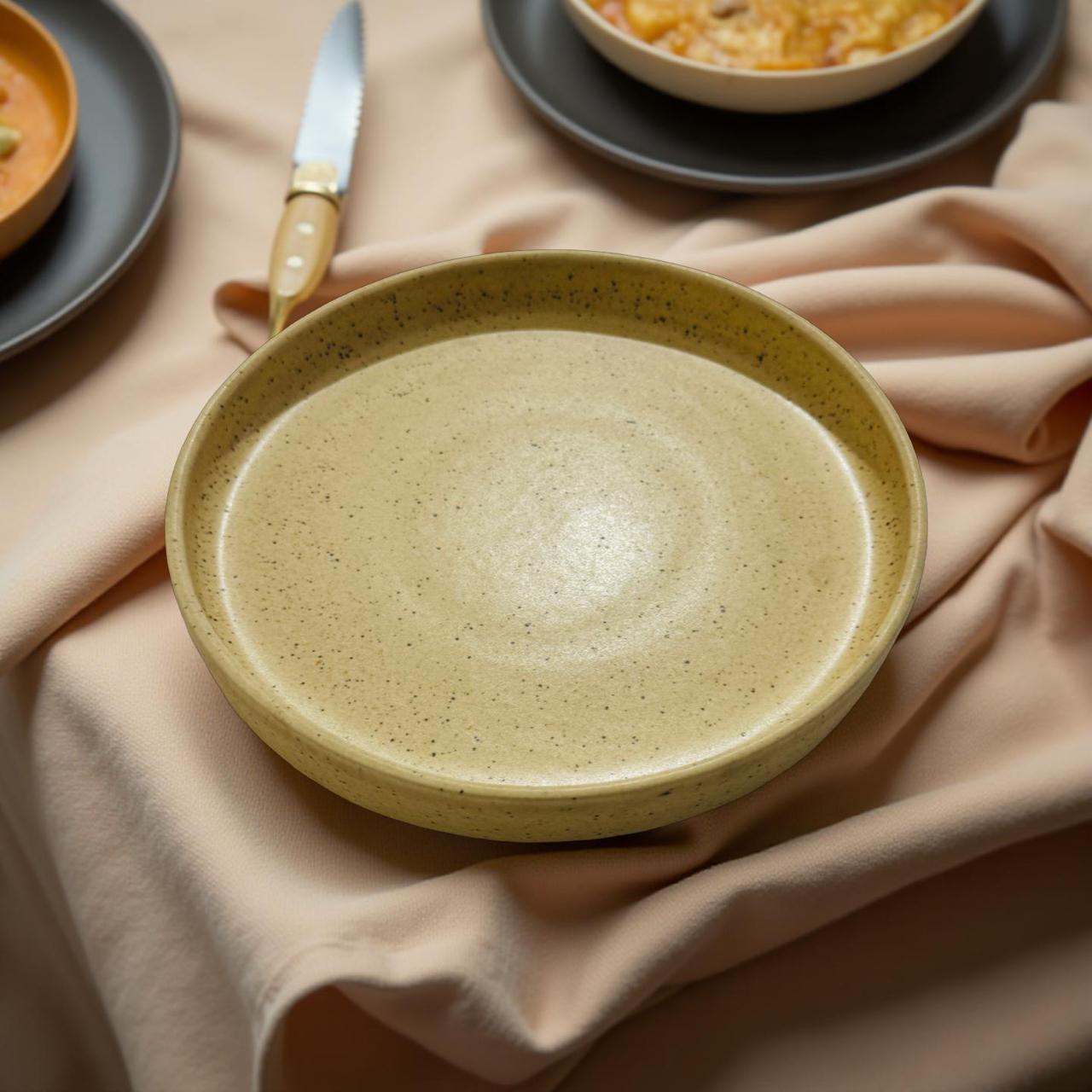 Beige ceramic plate on a beige cloth with a blurred background of other dishes.