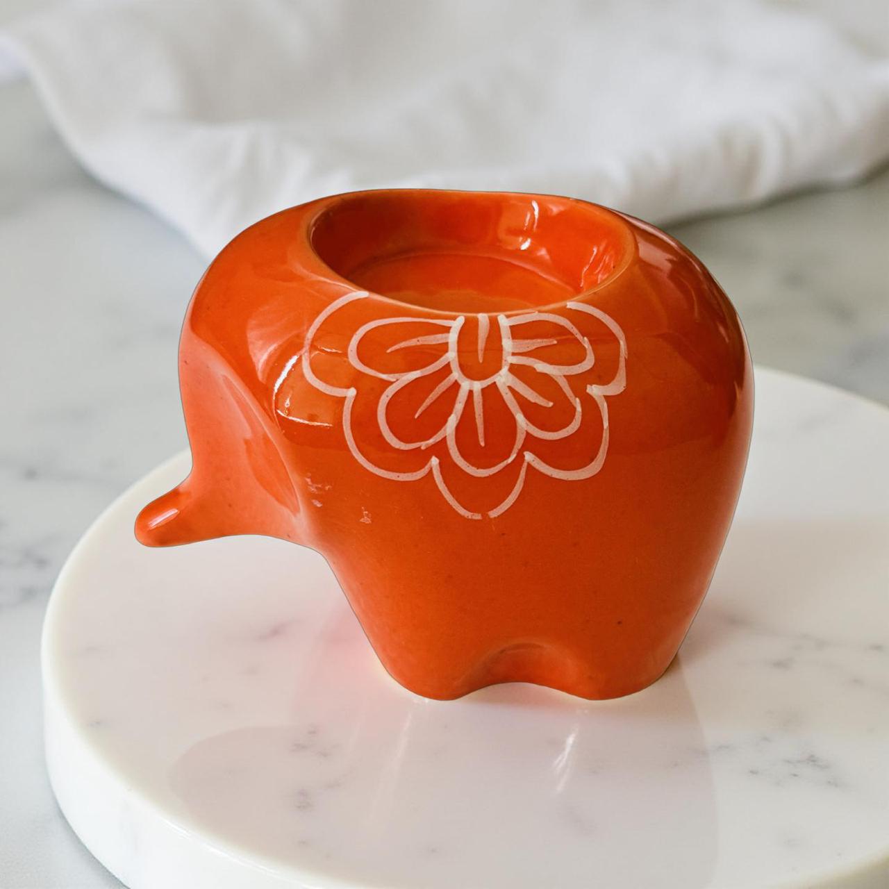 Orange ceramic elephant with floral design on a marble surface