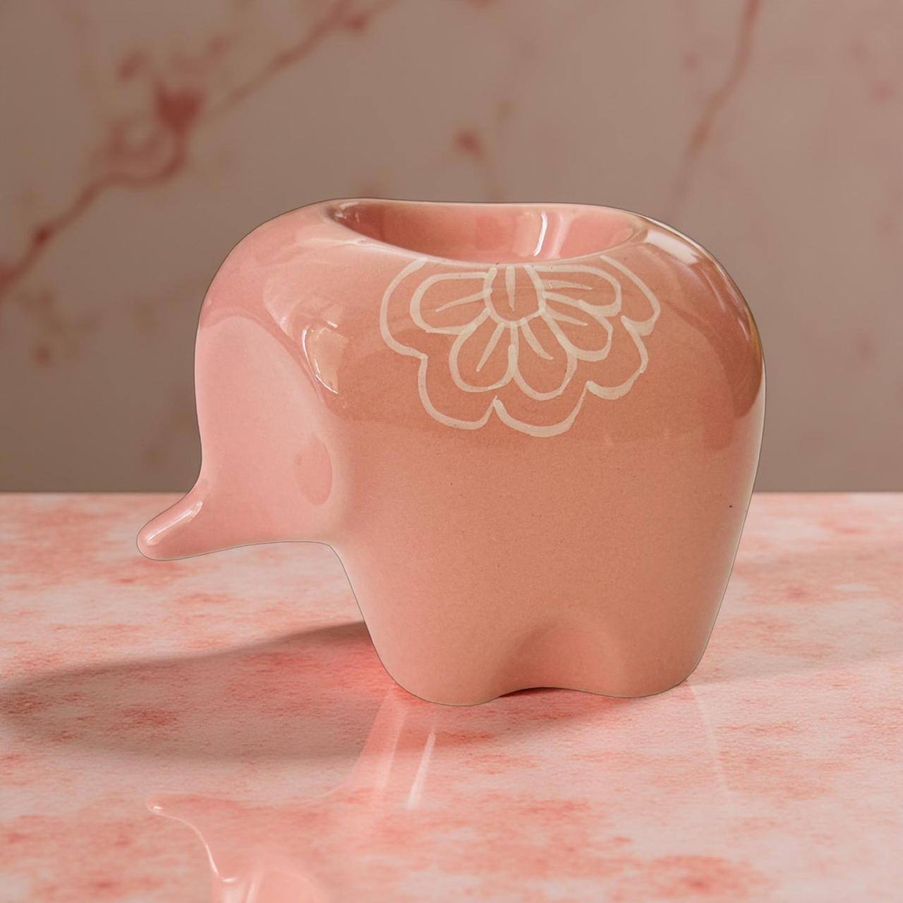 Pink elephant-shaped vase with floral design on a marble surface