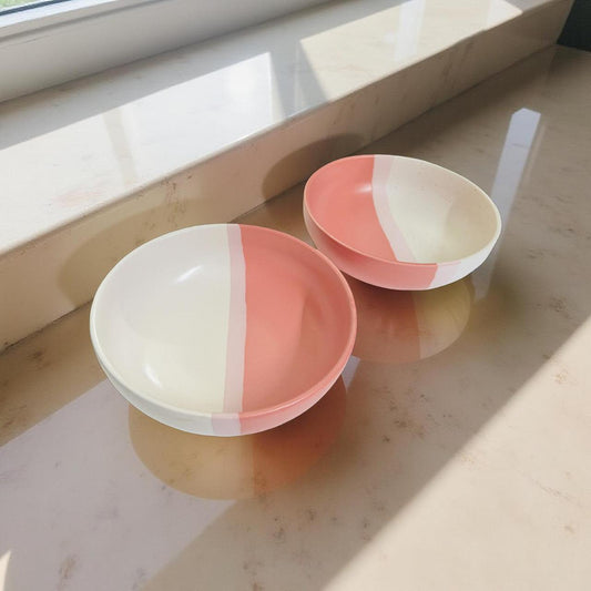 Two ceramic bowls with a two-tone design on a light surface.