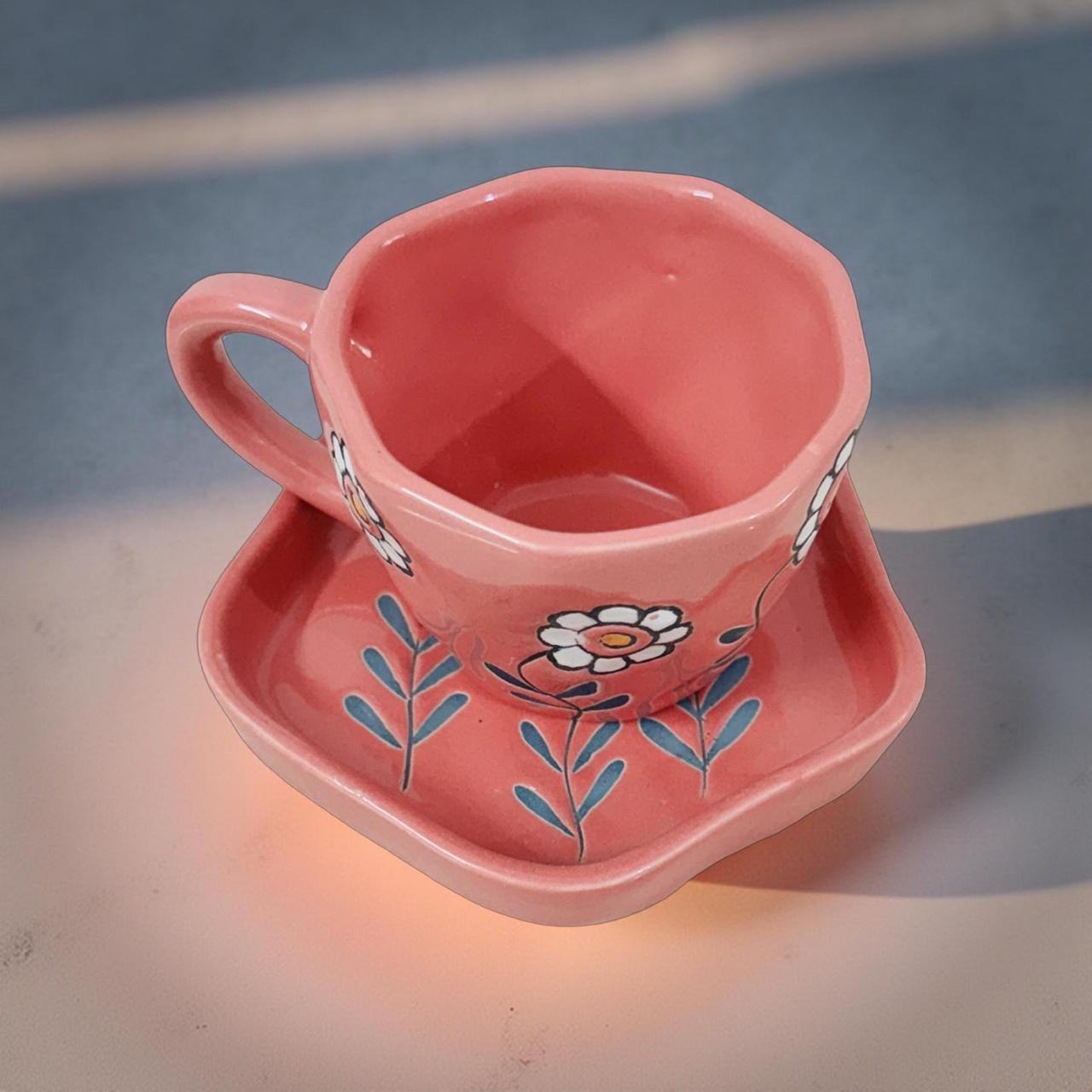 Close‑up view of pink ceramic tea cup with white daisy artwork