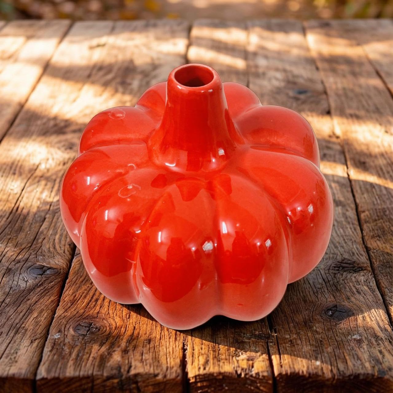 Red ceramic pumpkin-shaped vase on a wooden surface