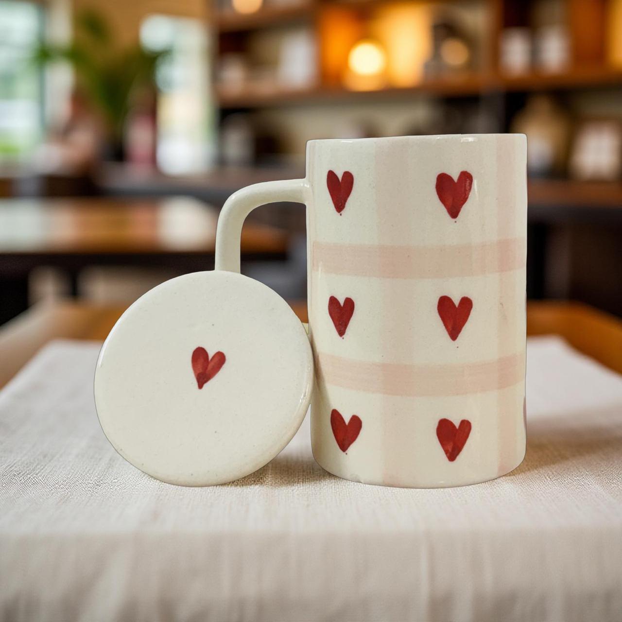Ceramic mug with red heart designs on a table in a cozy setting