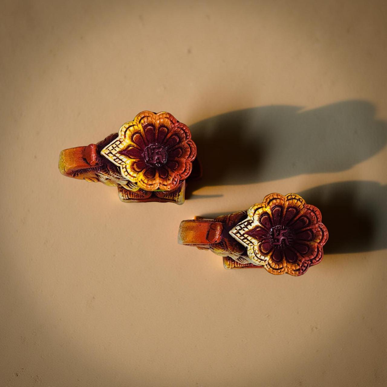 Decorative elephant candle holders with floral design on a beige background