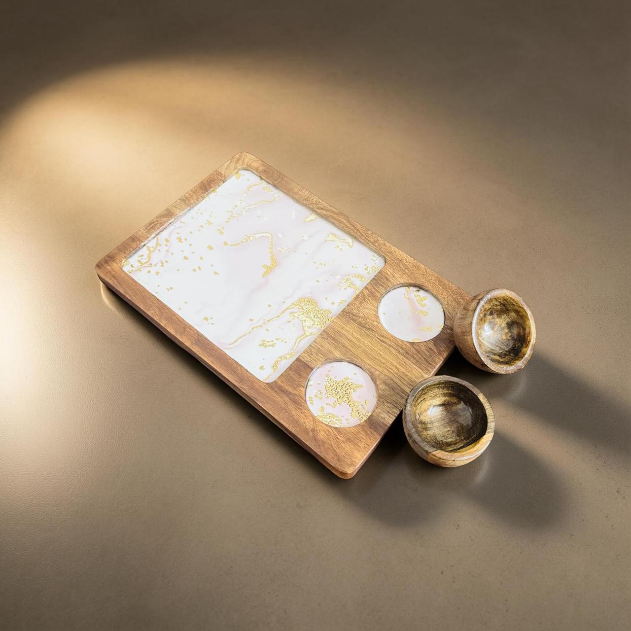 Wooden tray with marbleized surface and three small bowls on a brown background