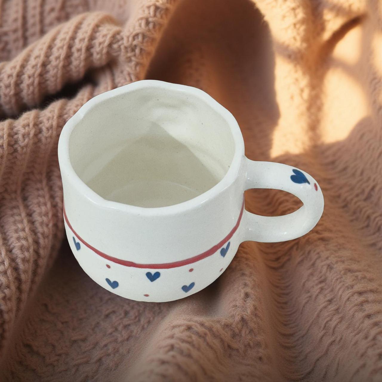 White ceramic mug with blue heart patterns on a textured brown surface