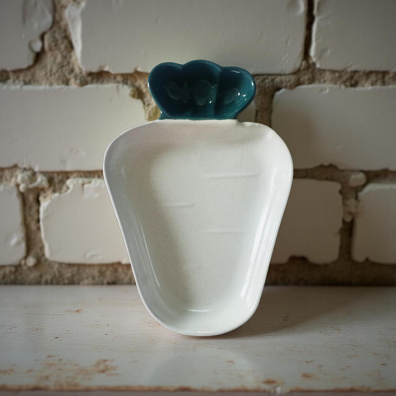 White ceramic dish with green top against a brick wall background