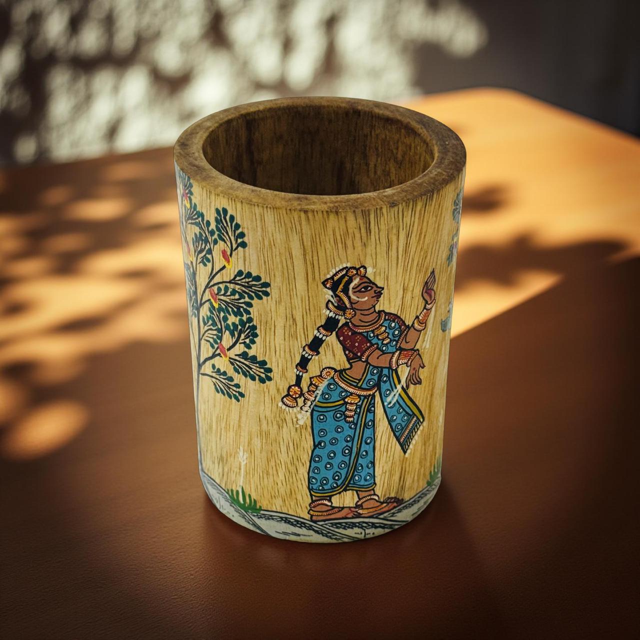 Wooden vase with artistic depiction of a person and foliage on a wooden surface