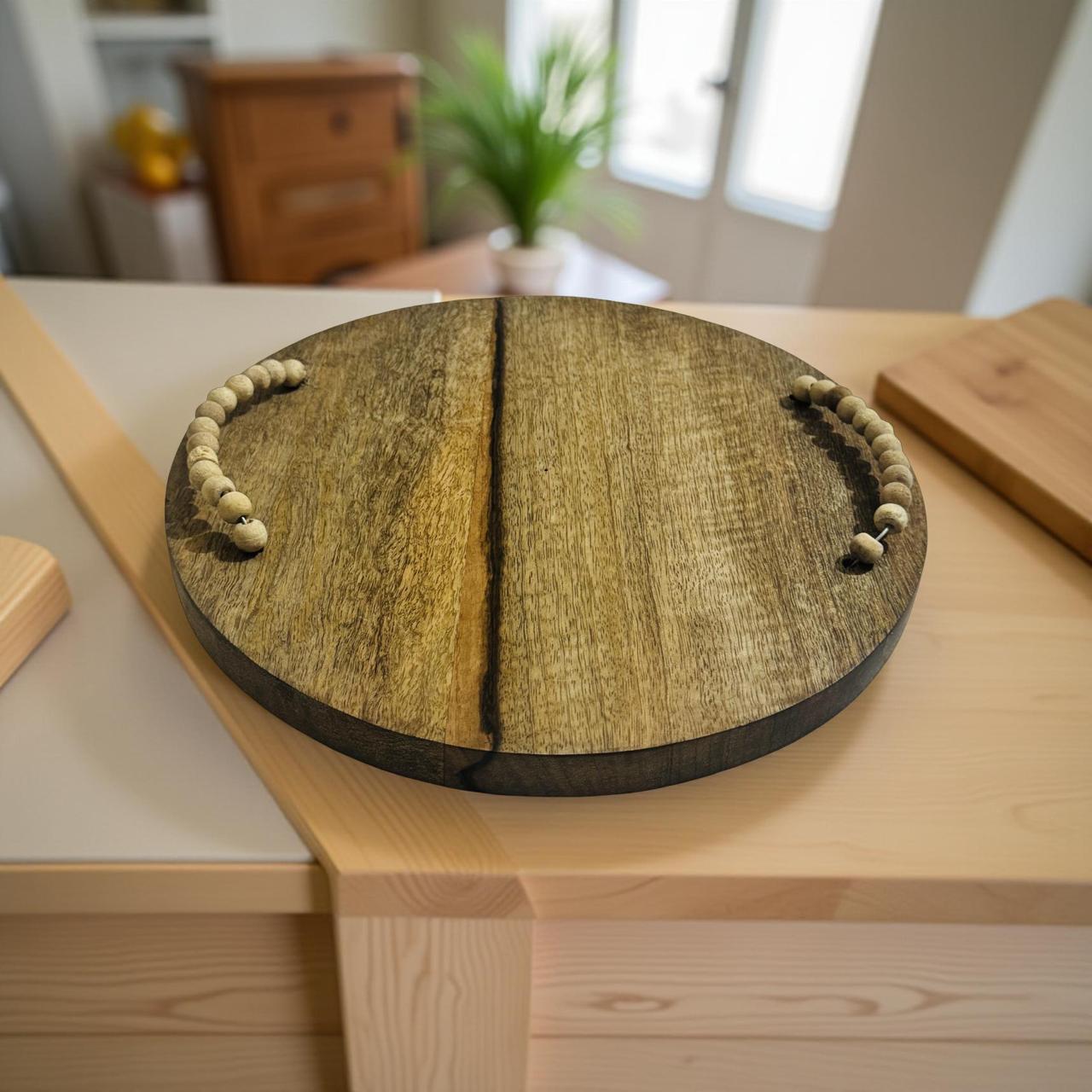 Round wooden cutting board with beaded handles on a kitchen counter.