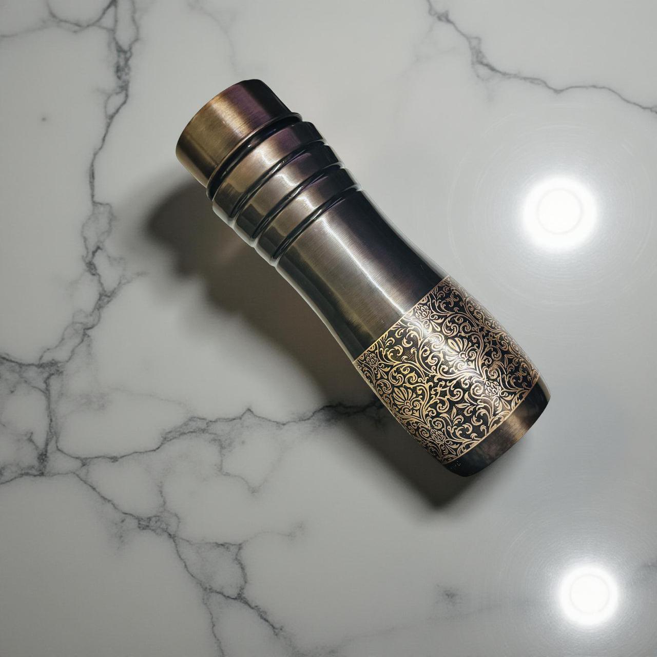 Decorative metal water bottle with intricate design on a marble surface