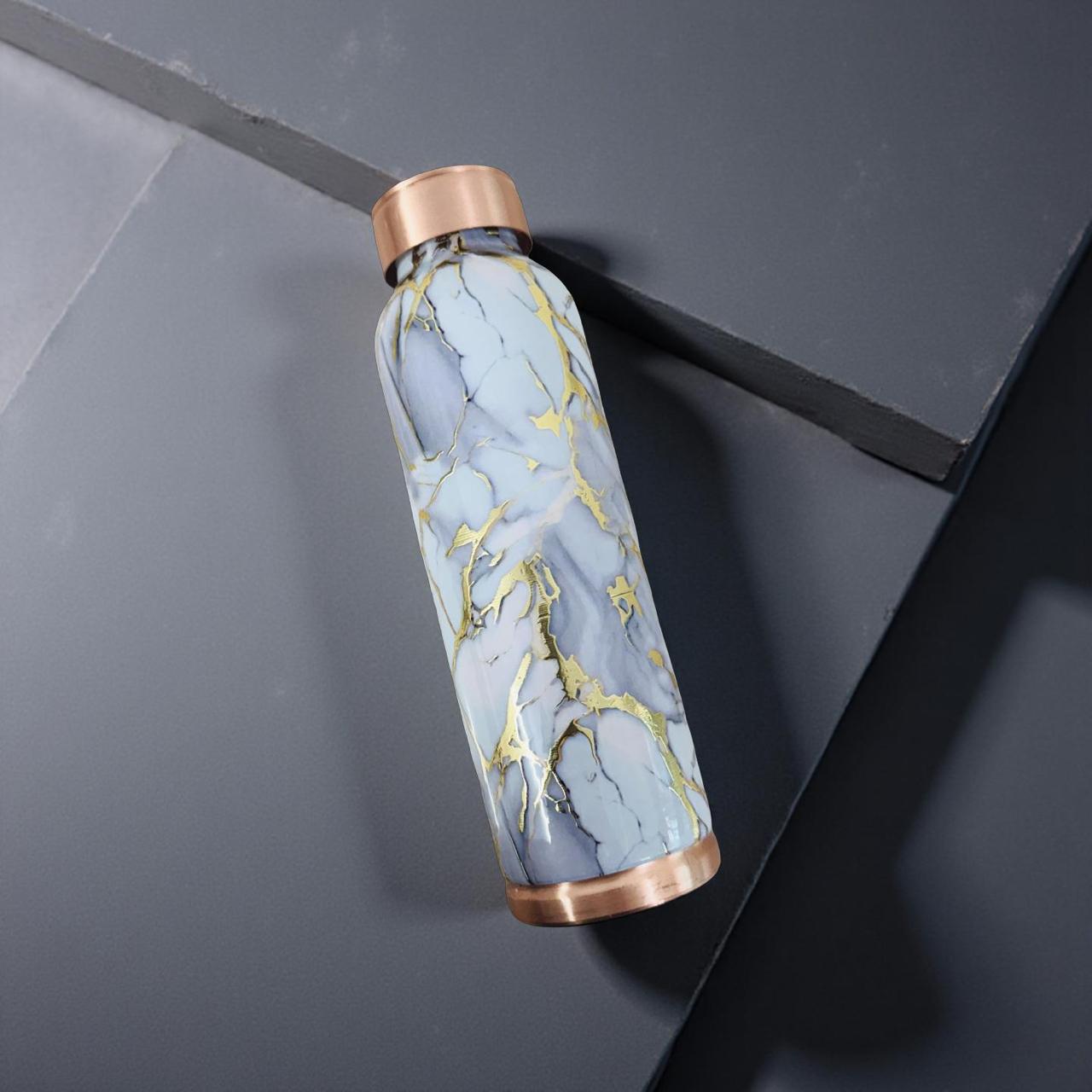 Marble-patterned water bottle with bronze cap on a dark surface
