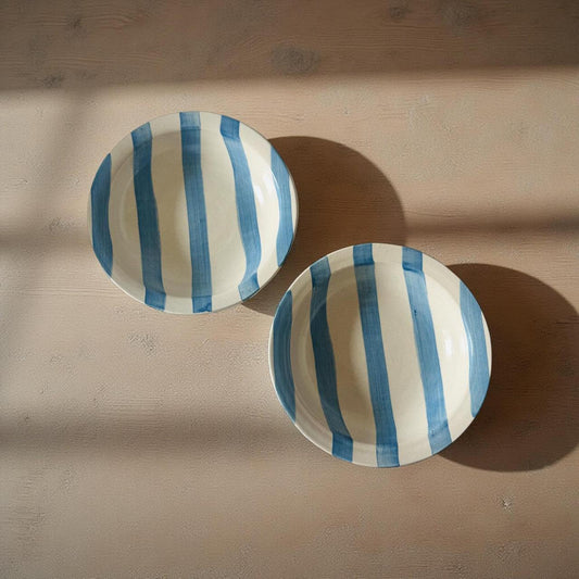 Two ceramic plates with blue and white stripes on a wooden surface
