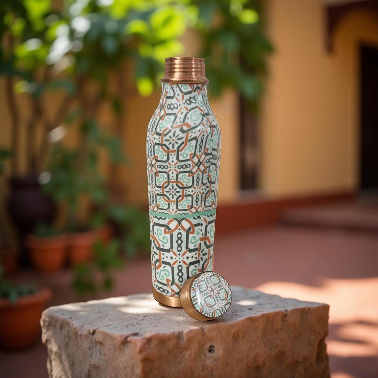 Decorative water bottle with geometric pattern on a stone surface outdoors