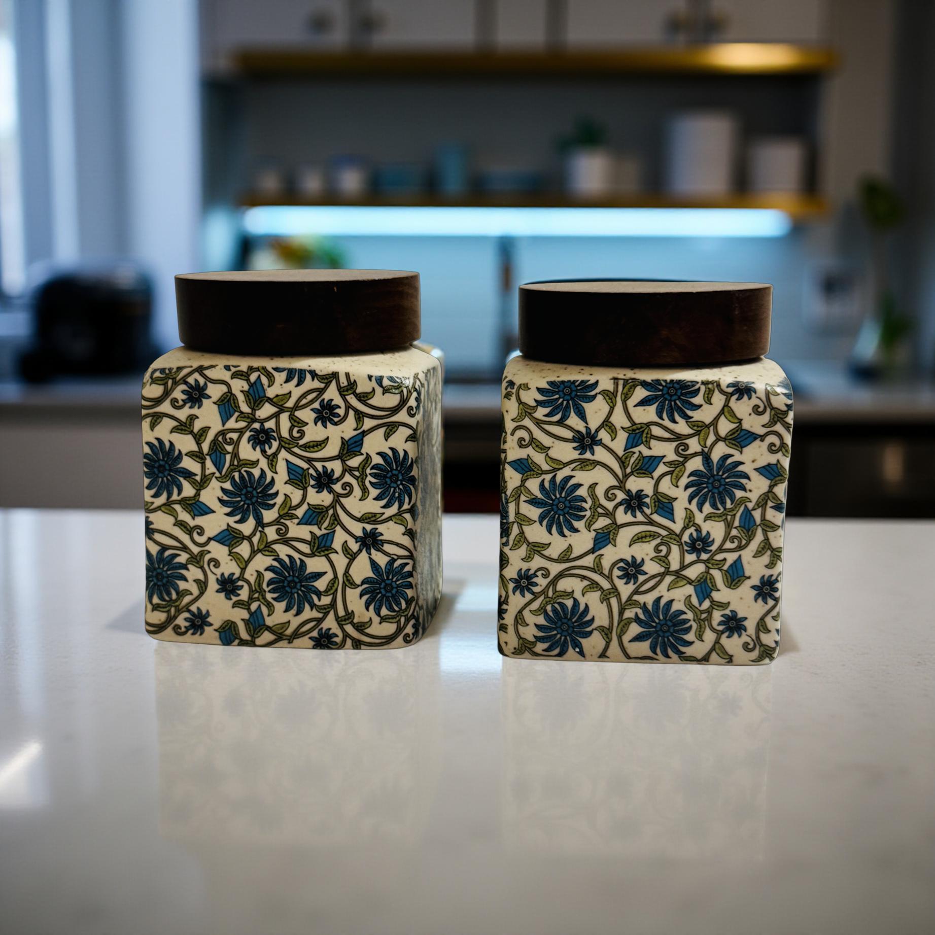 Two decorative jars with floral patterns on a reflective surface.