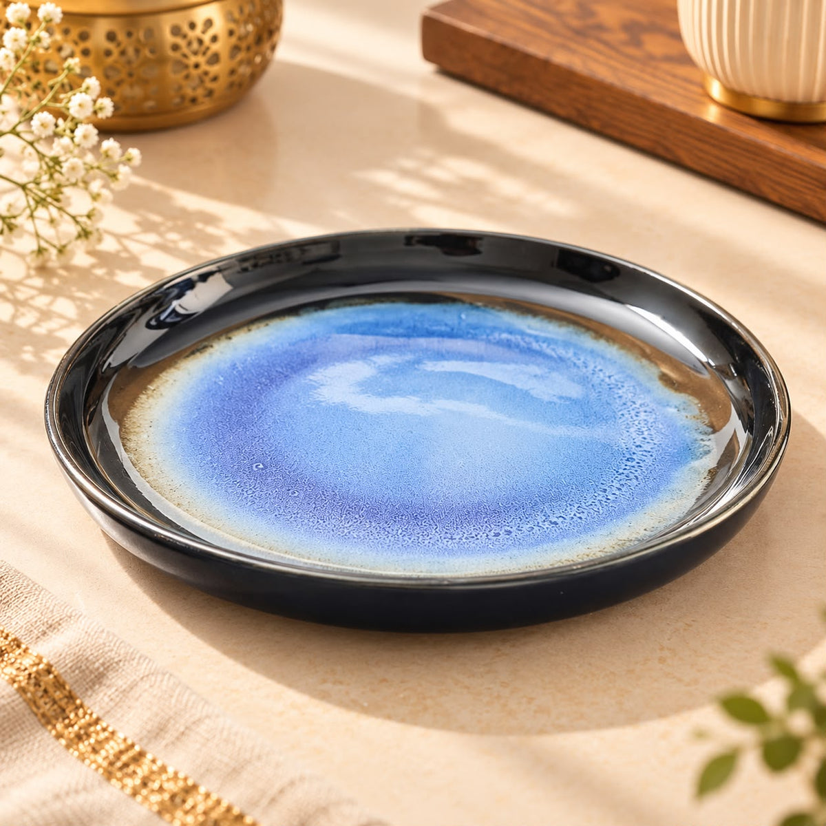 Blue ceramic serving plate styled with tea-time snacks on a warm neutral tabletop.