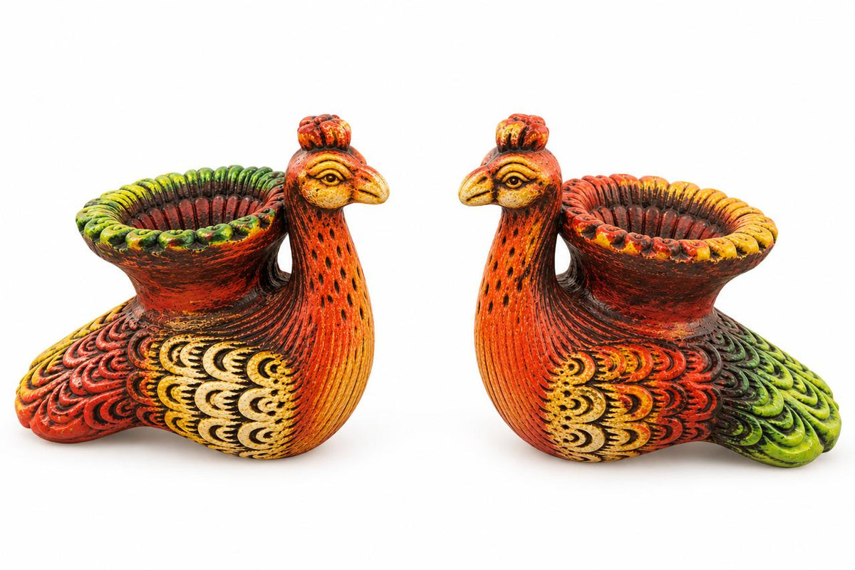 A pair of hand-painted peacock figurines with vibrant red, orange, yellow, and green patterns, set against a plain white background.